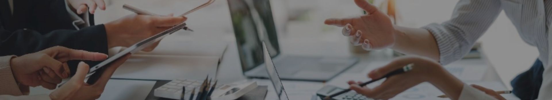 Mains d'hommes et de femmes au dessus d'un bureau avec ordinateurs, stylos, documents