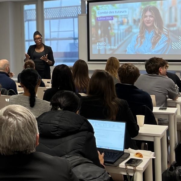 Femme fait un conférence face à un audience dans une salle de classe