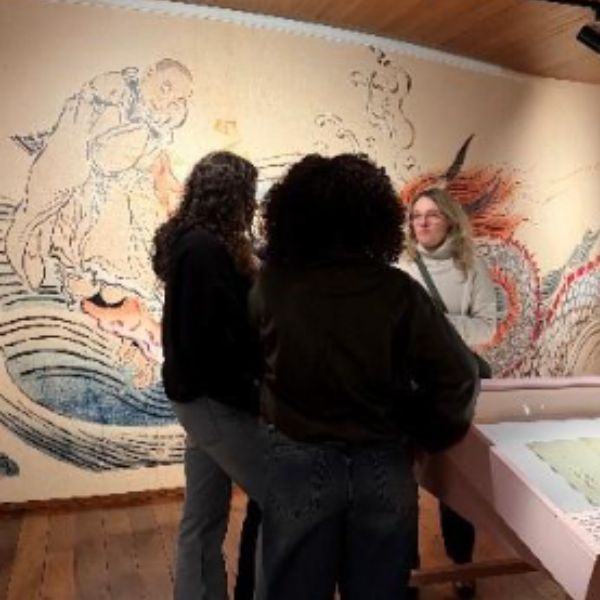 Deux étudiantes dos à la caméra et leur professeure face caméra discutent 