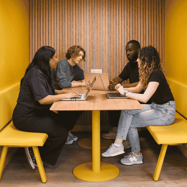 Groupe d'étudiants autour d'une table travaille sur un projet de groupe dans une salle jaune