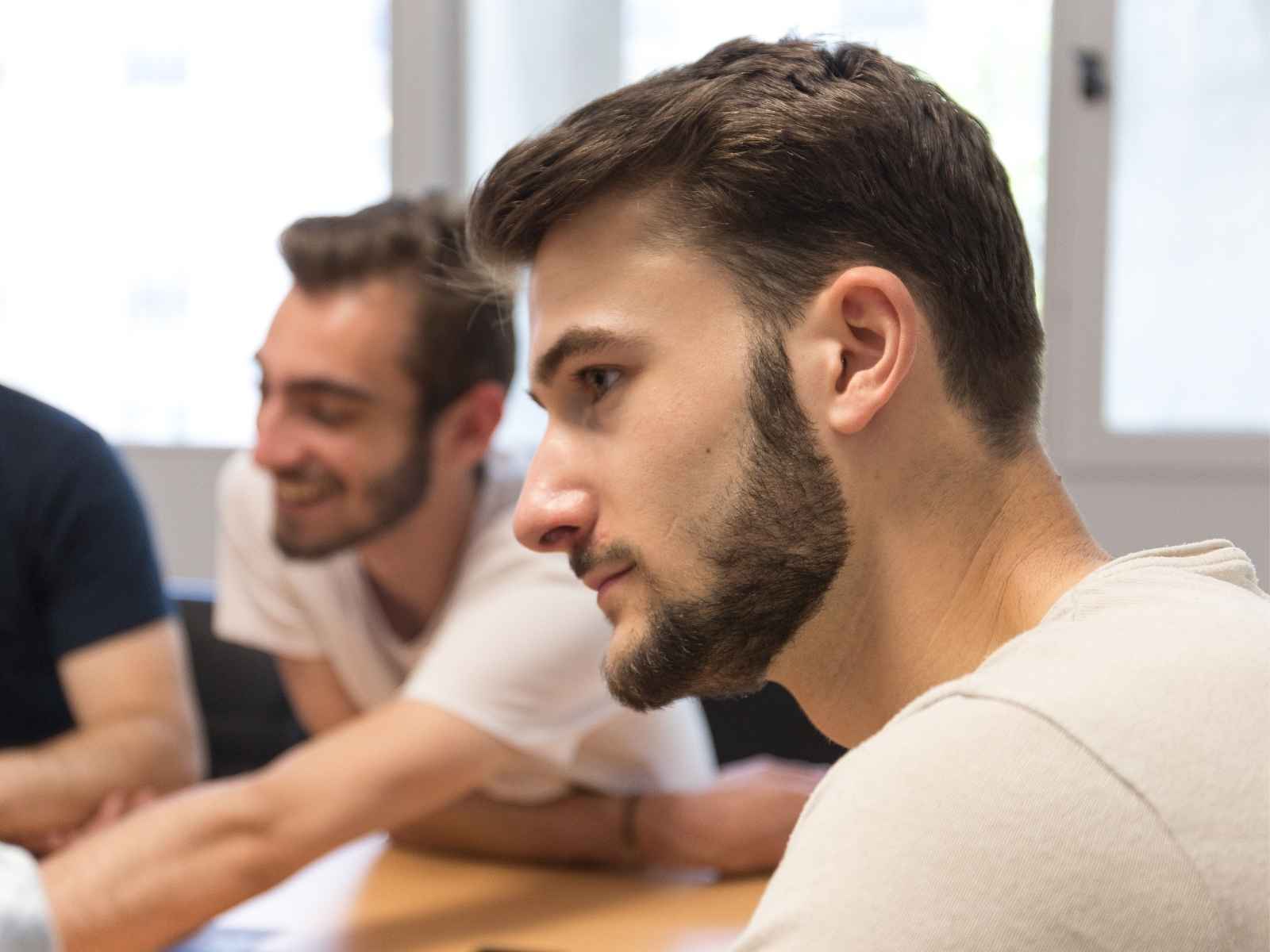 Jeune homme brun de profil avec une barbe, en t-shirt blanc