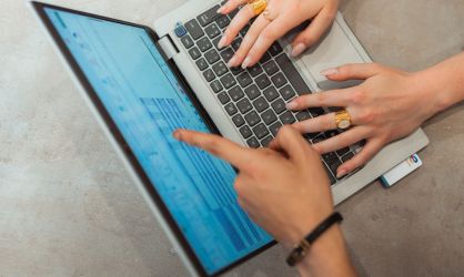 Vue de haut d'un ordinateur avec des mains d'étudiantes tapant sur le clavier et une main d'étudiant qui pointe du doigt l'écran