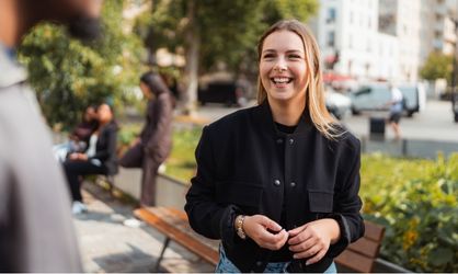 Jeune femme blonde en veste noire qui sourit