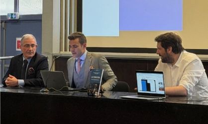 Trois hommes sont assis à un bureau face caméra pour une conférence